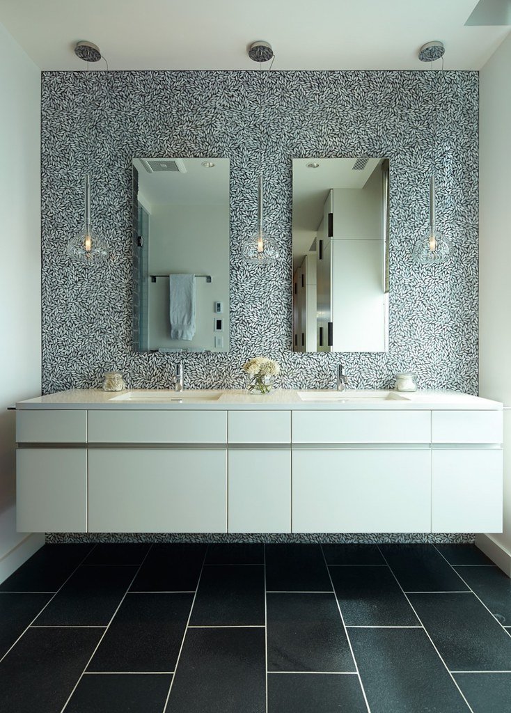 Modern bathroom vanity with twin mirrors, pendant lights, and a patterned accent wall.