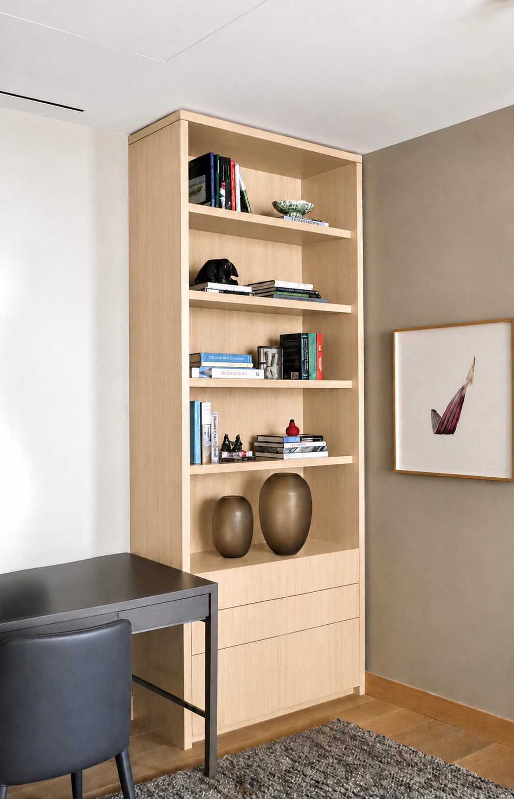 A light wood bookshelf with decorative objects, books, and small sculptures in a modern living space.