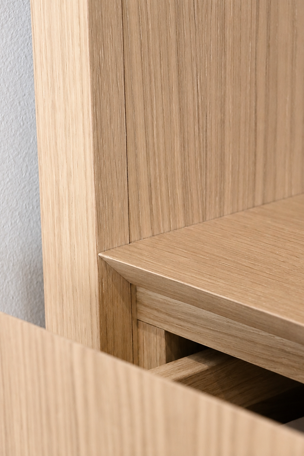Close-up of a wooden piece of furniture, showing clean lines and a smooth finish, with a corner and part of an open drawer or shelf.