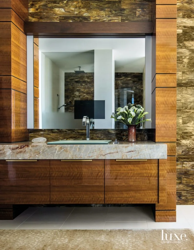 Modern bathroom with a freestanding bathtub, double vanity with two sinks, large mirror, natural wood cabinets, and a window with a view of greenery.