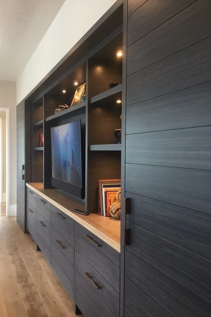 Modern wall unit with a flat-screen TV, open shelves, and closed cabinets in a living room.