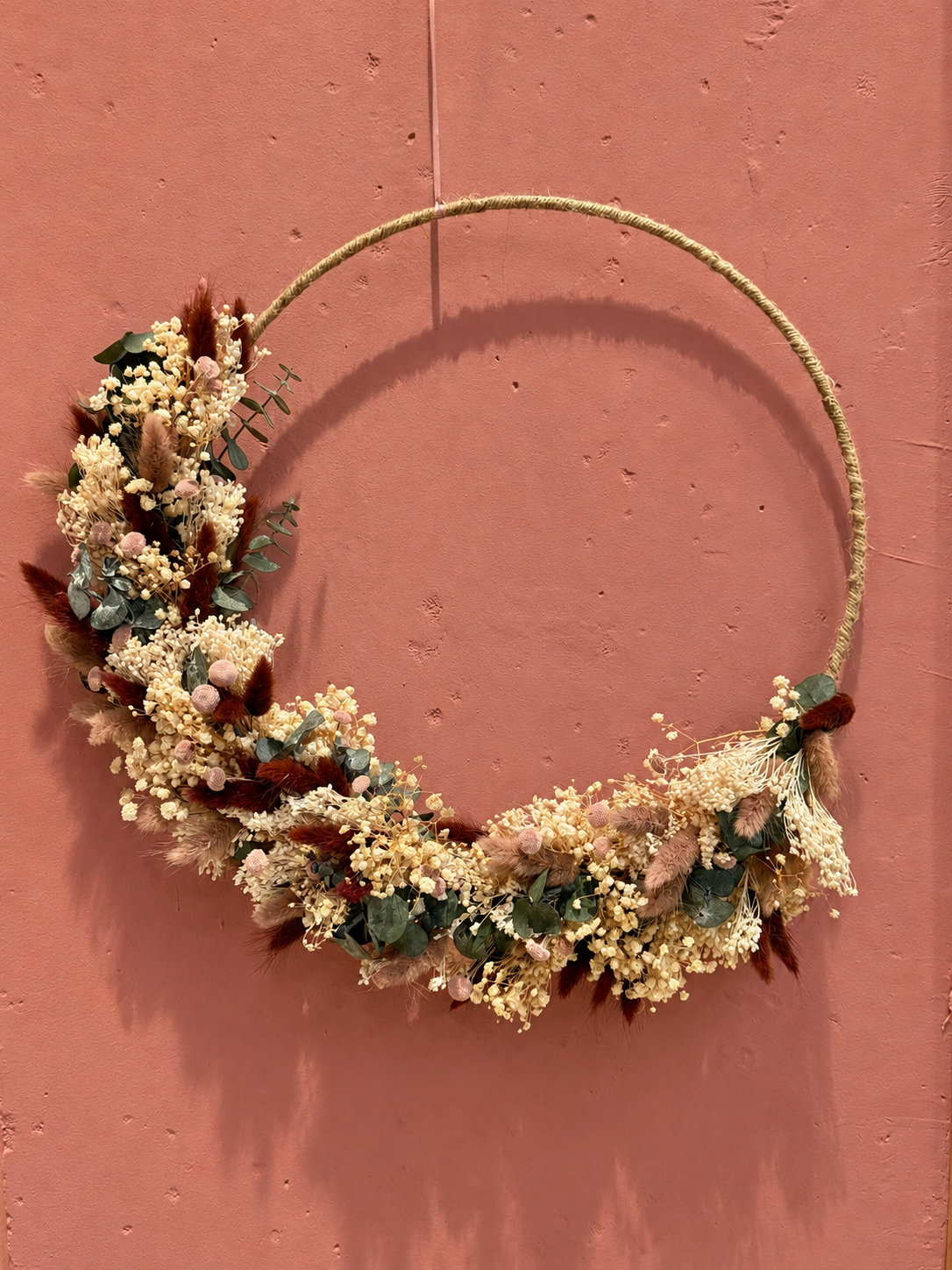 Getrockneter Blumenkranz an rosafarbener Wand.png