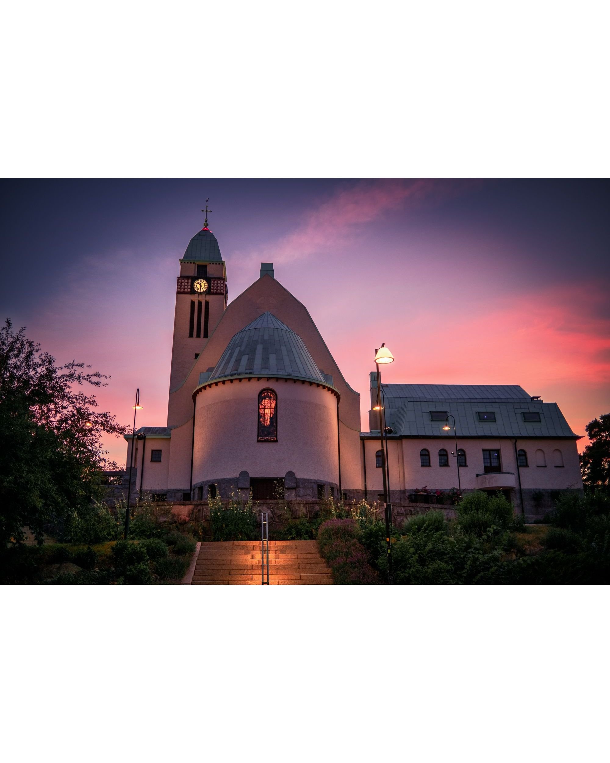 Sundbyberg Church glowing at dusk under a pink and purple sky, stained glass window lit from within — fine art photography print