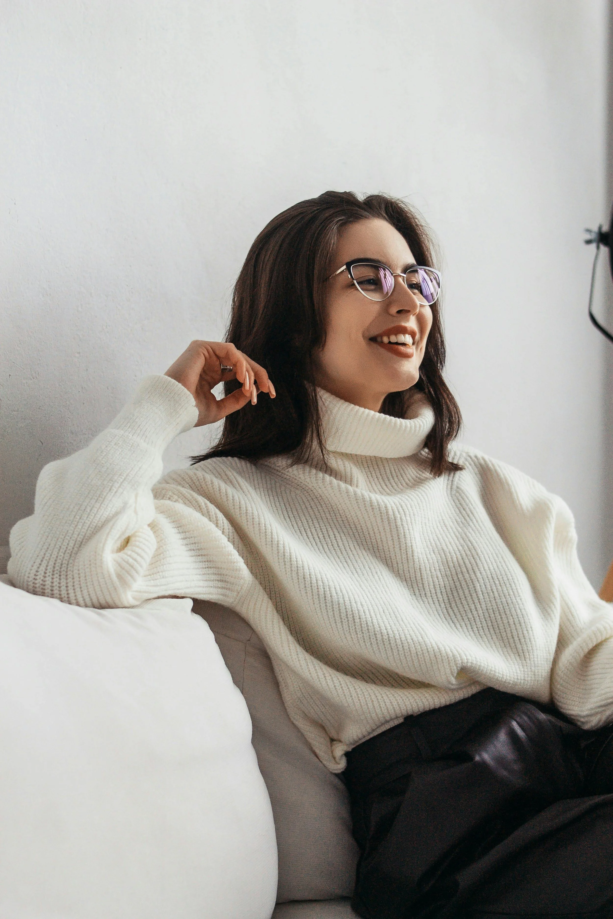 Woman sitting on a couch, smiling softly while connecting with someone, representing comfort and trust in depression therapy.