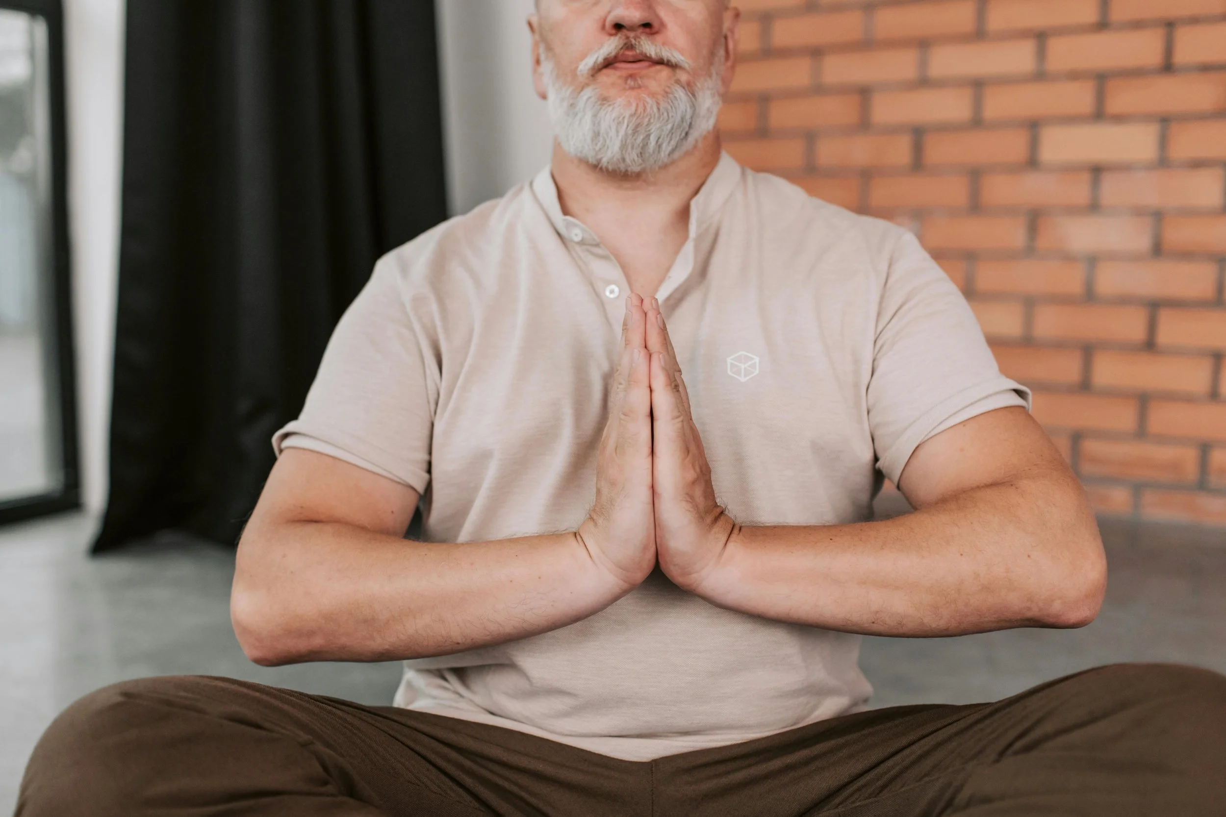 Man meditating with eyes closed, practicing grounding and regulation techniques to stay present during trauma recovery.