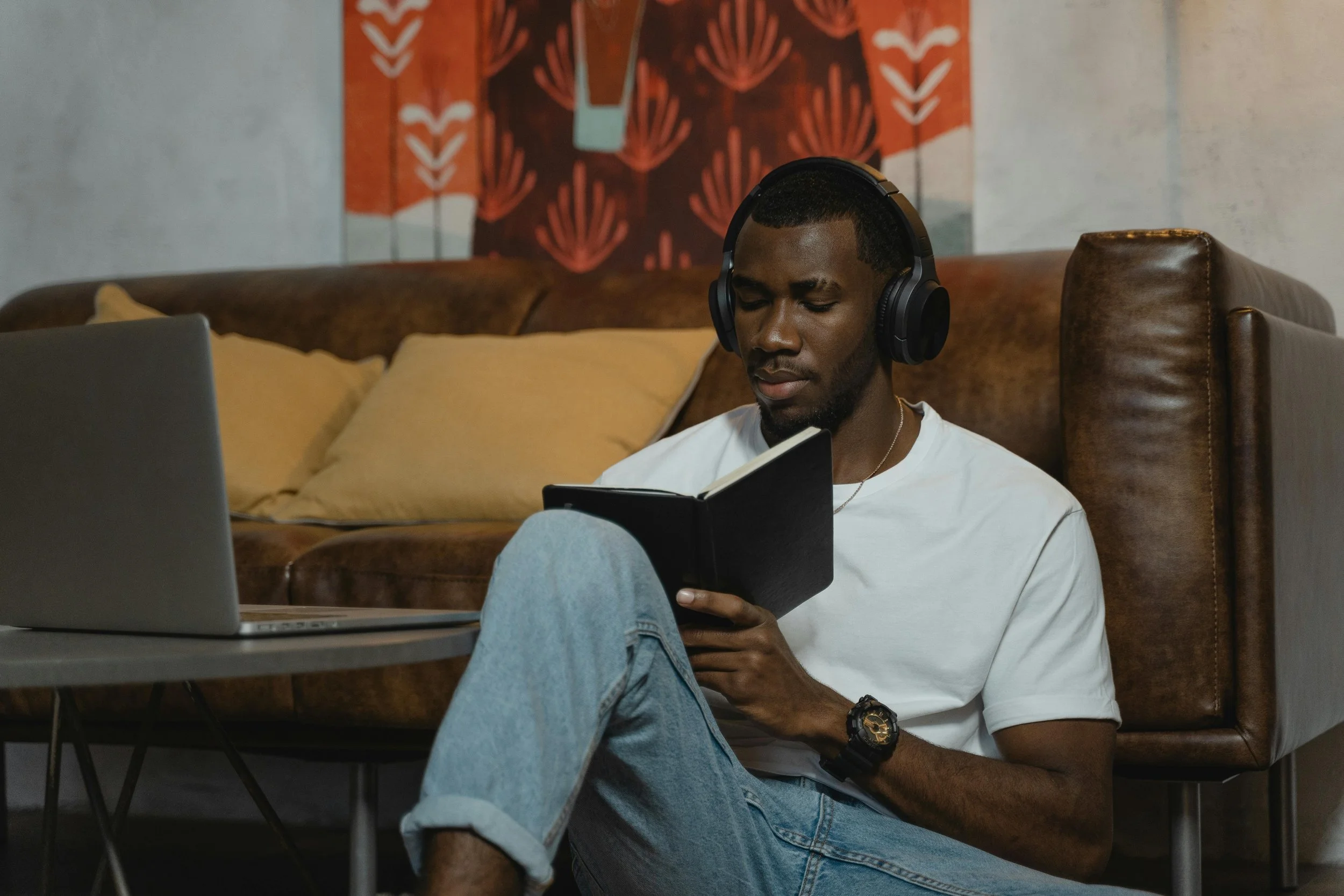 Man sitting on the floor in front of a couch, wearing headphones and writing, symbolizing safe, supported processing during trauma therapy.