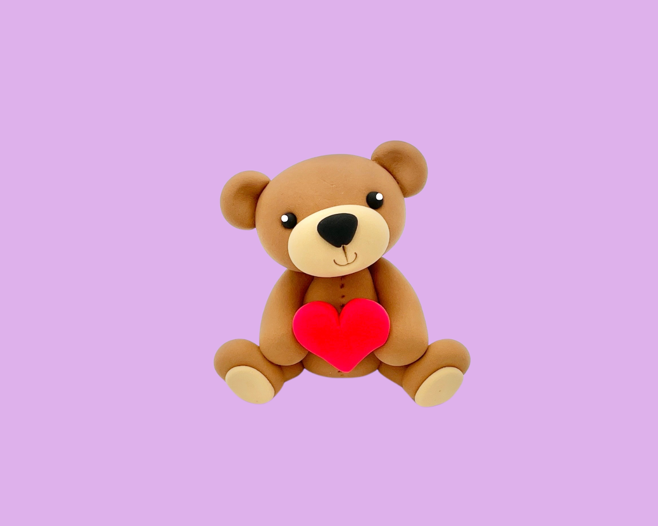 A cute teddy bear plush toy holding a red heart, sitting on a light purple background.