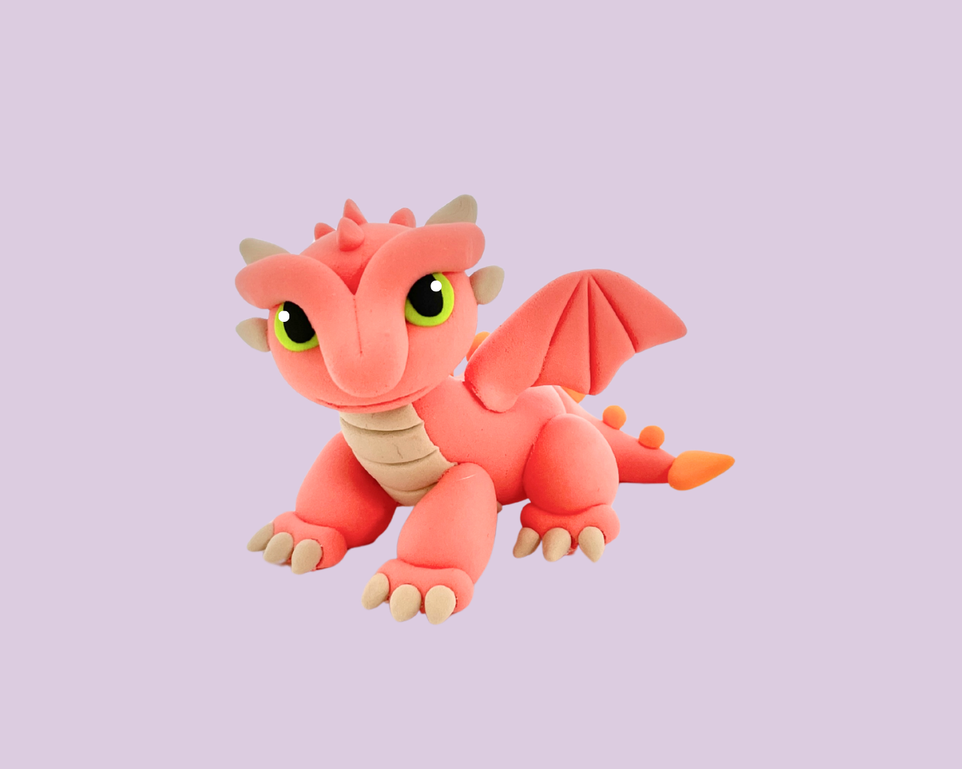 Pink plush dragon toy with green eyes, small horns, and wings, sitting on a light purple background.