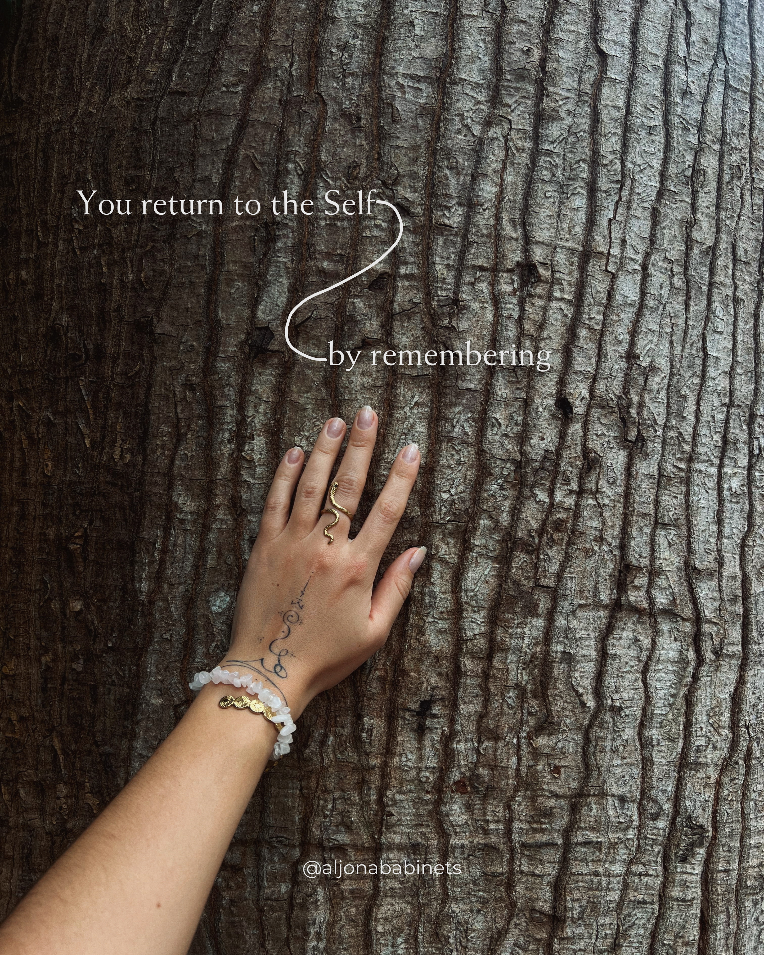 Close-up of a hand with a tattoo, wearing a gold ring and bracelets, resting on the bark of a tree with an inspirational quote overlaid: 'You return to the Self by remembering'.