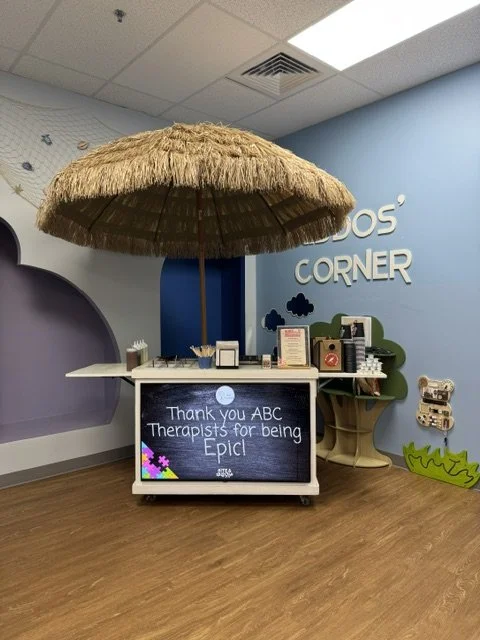 A small reception area with a thatched umbrella over a desk, thanking ABC therapists for being epic, in a colorful children's therapy center.