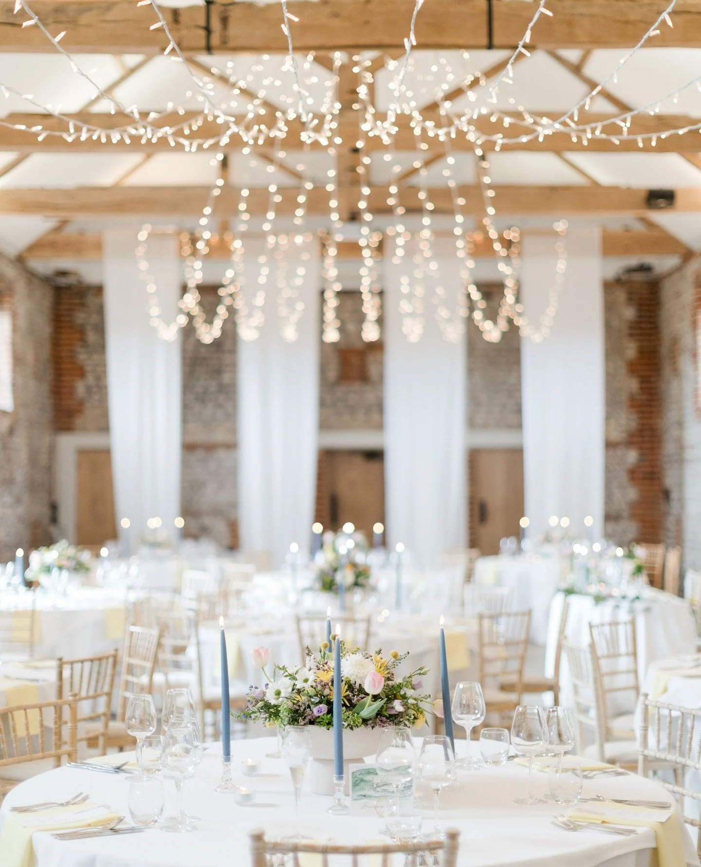 Central Apex || Installed overhead in two graceful V formations, meeting⁠ at a central point before gently fanning softly across⁠ the beams. A refined arrangement creating soft light,⁠ drawing the eye upward and adding depth and elegance⁠ to the barn