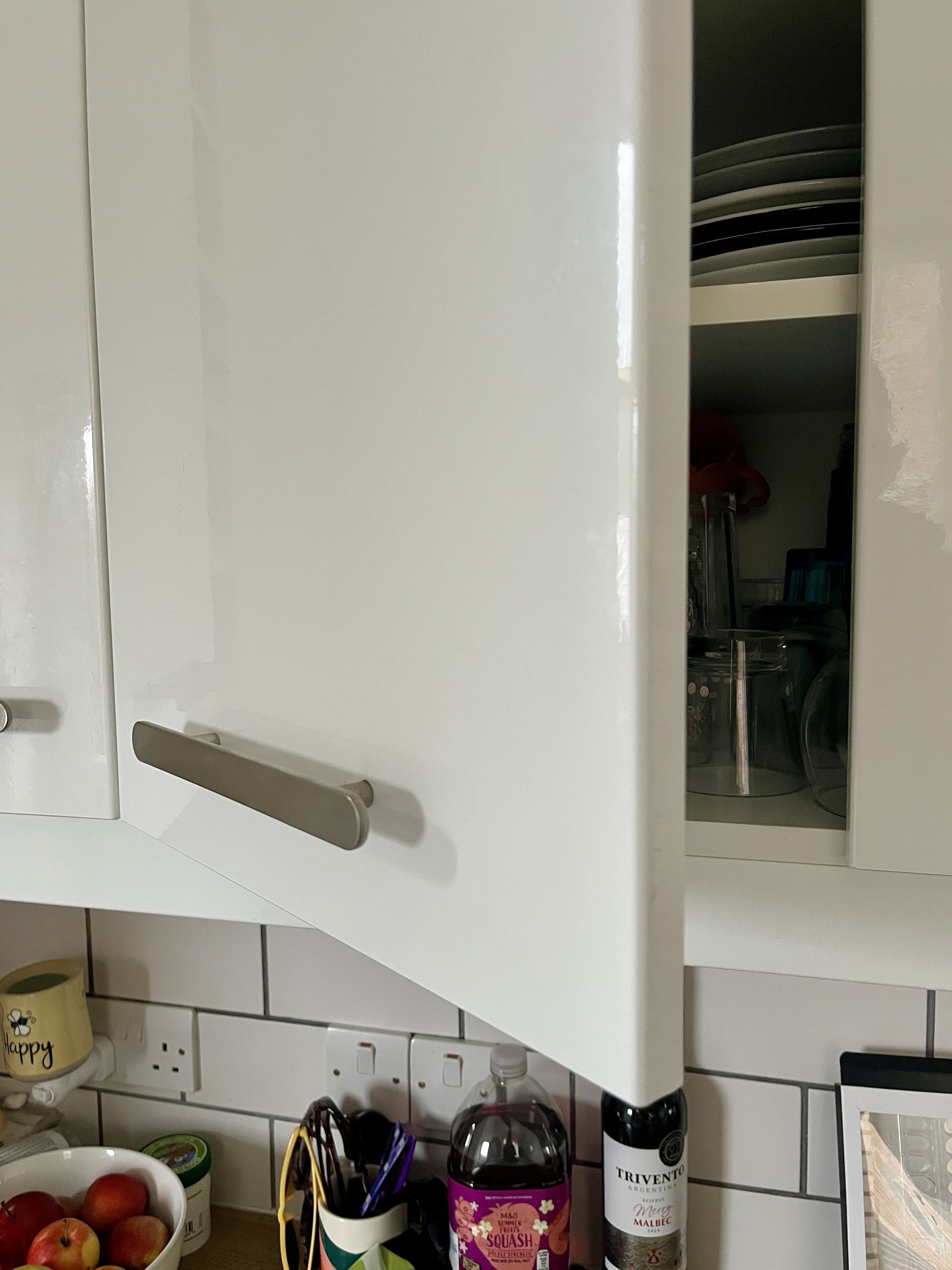 Take a photo of a cabinet door slightly open, showing the door’s edge, the condition of the underlying material, and the edge of the cabinet frame as well.