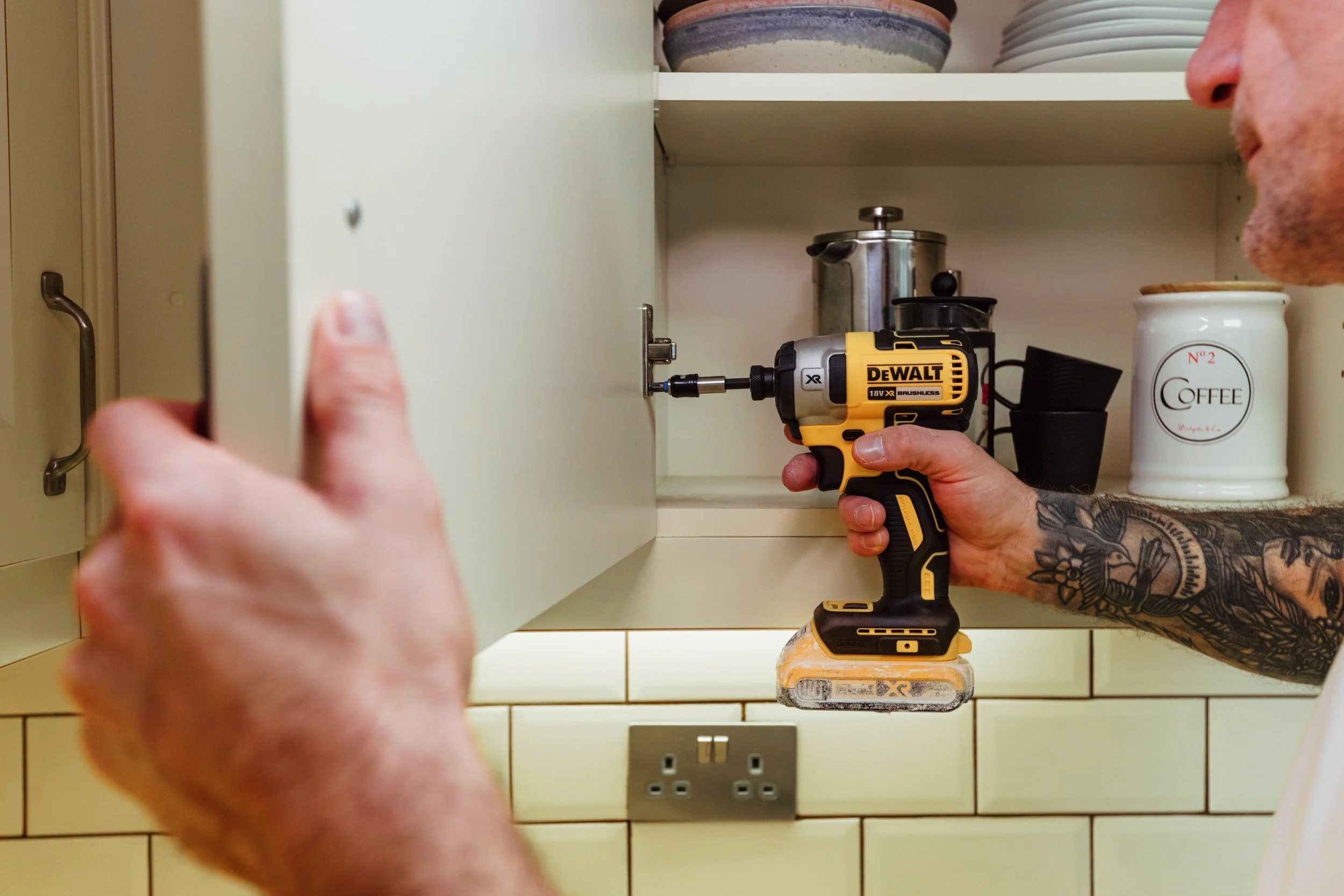 Person wearing black gloves smoothing out a black rubber flooring tile with a gray sponge roller.