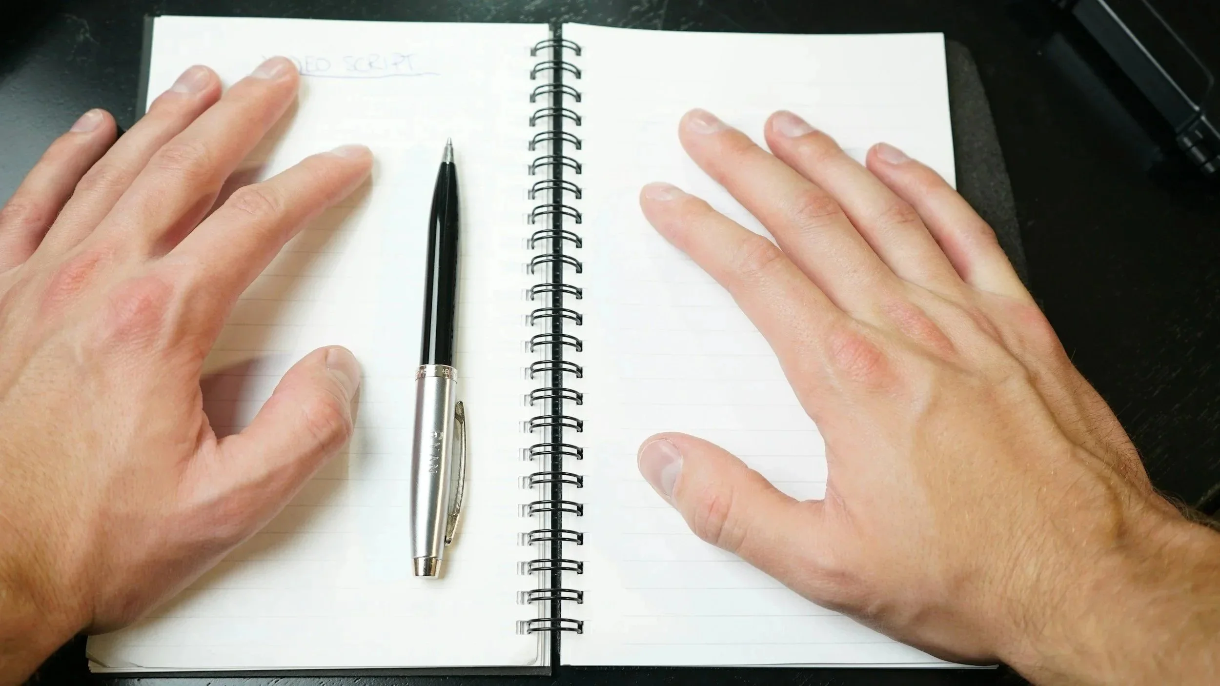 A diary, pen and two hands next to it