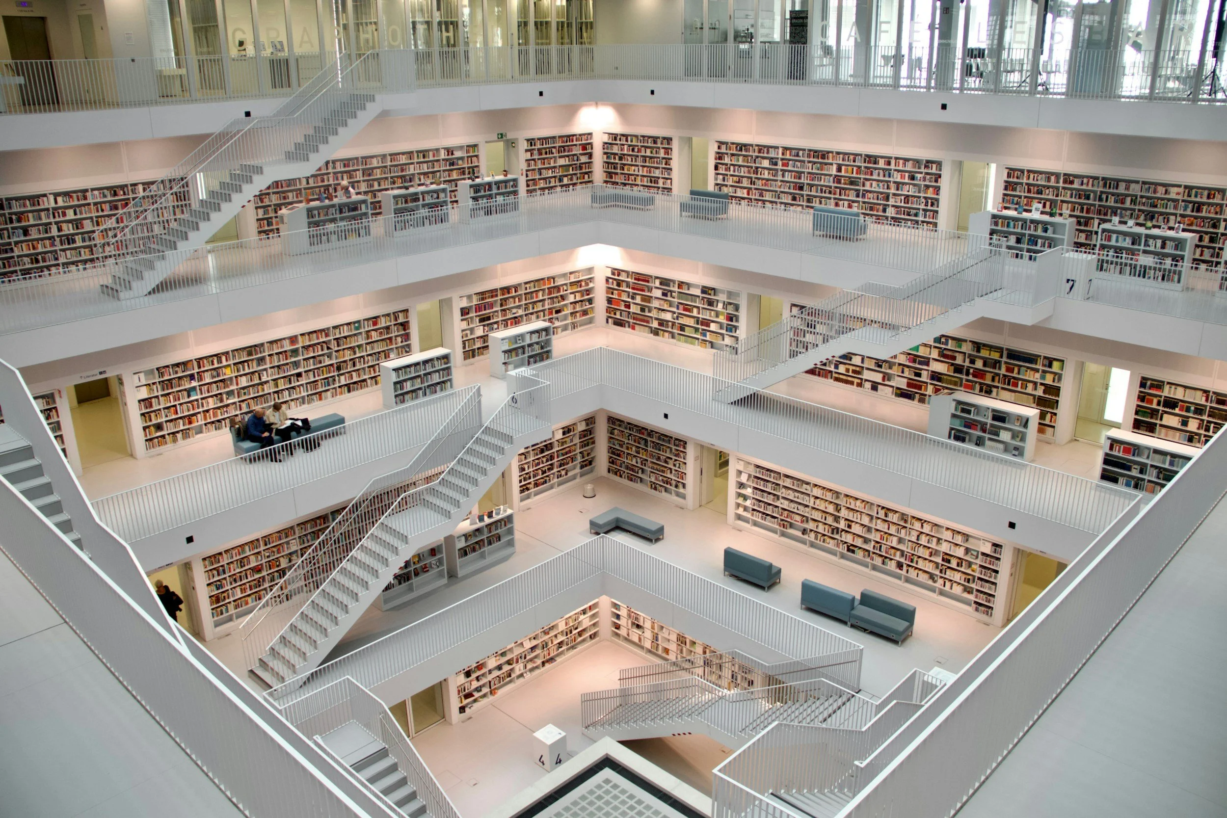 Multiple floors of a modern, white library with bookshelves filled with books and metal staircases connecting each level.