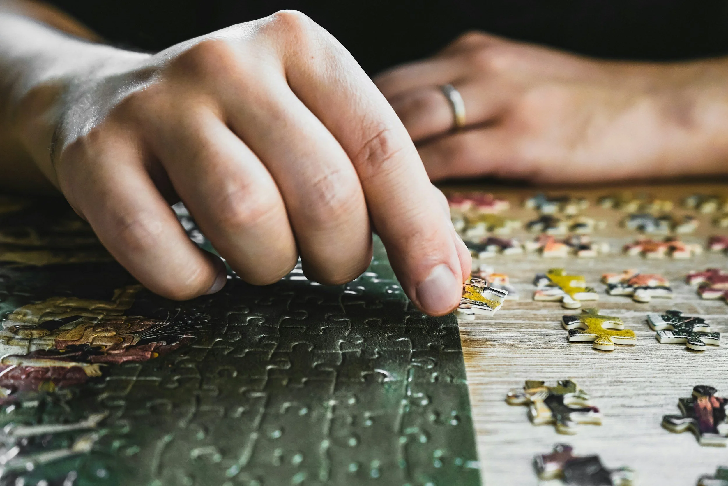 A person two hands completing a jigsaw puzzle