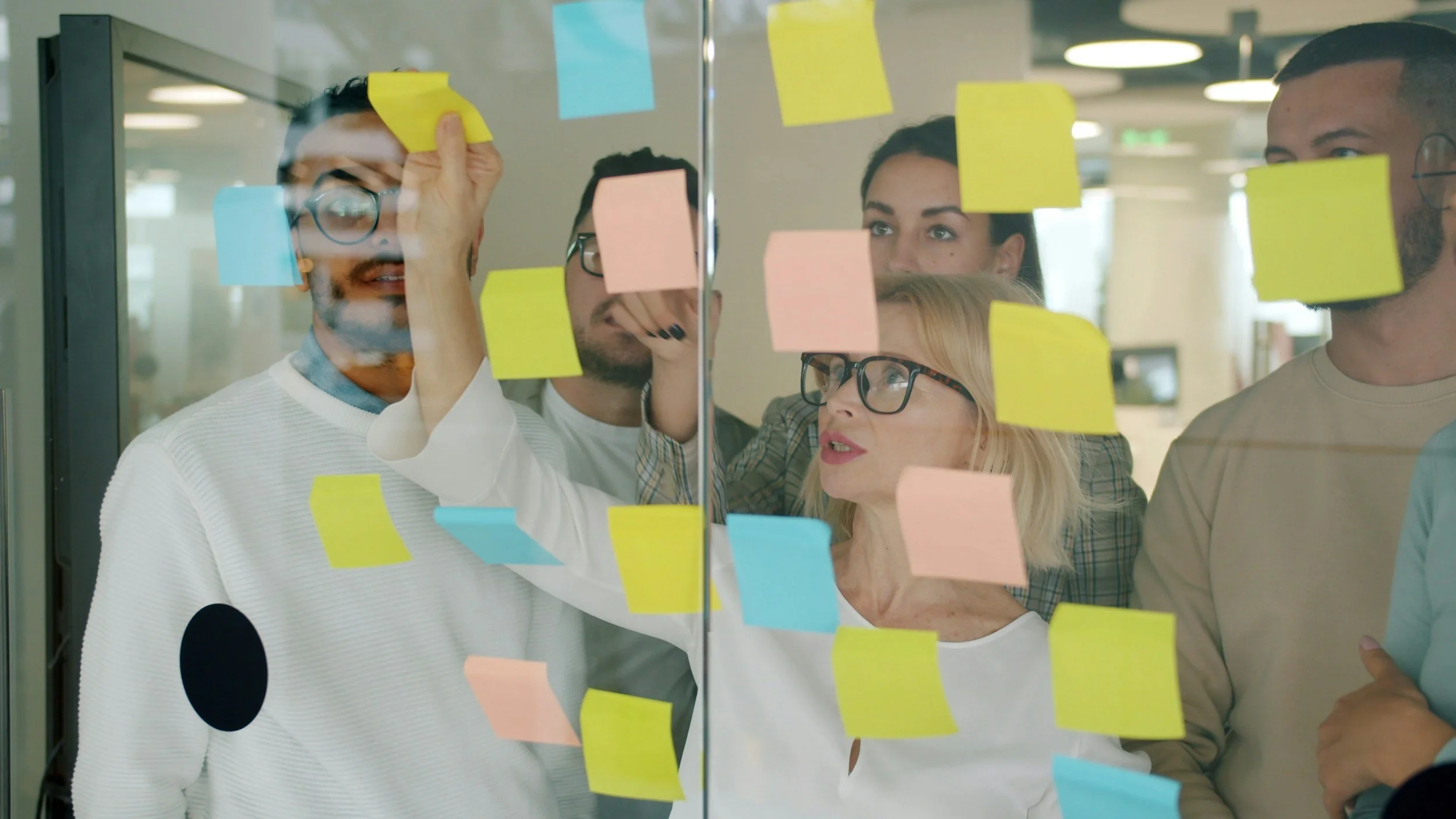 a group of people putting post it notes on a glass wall