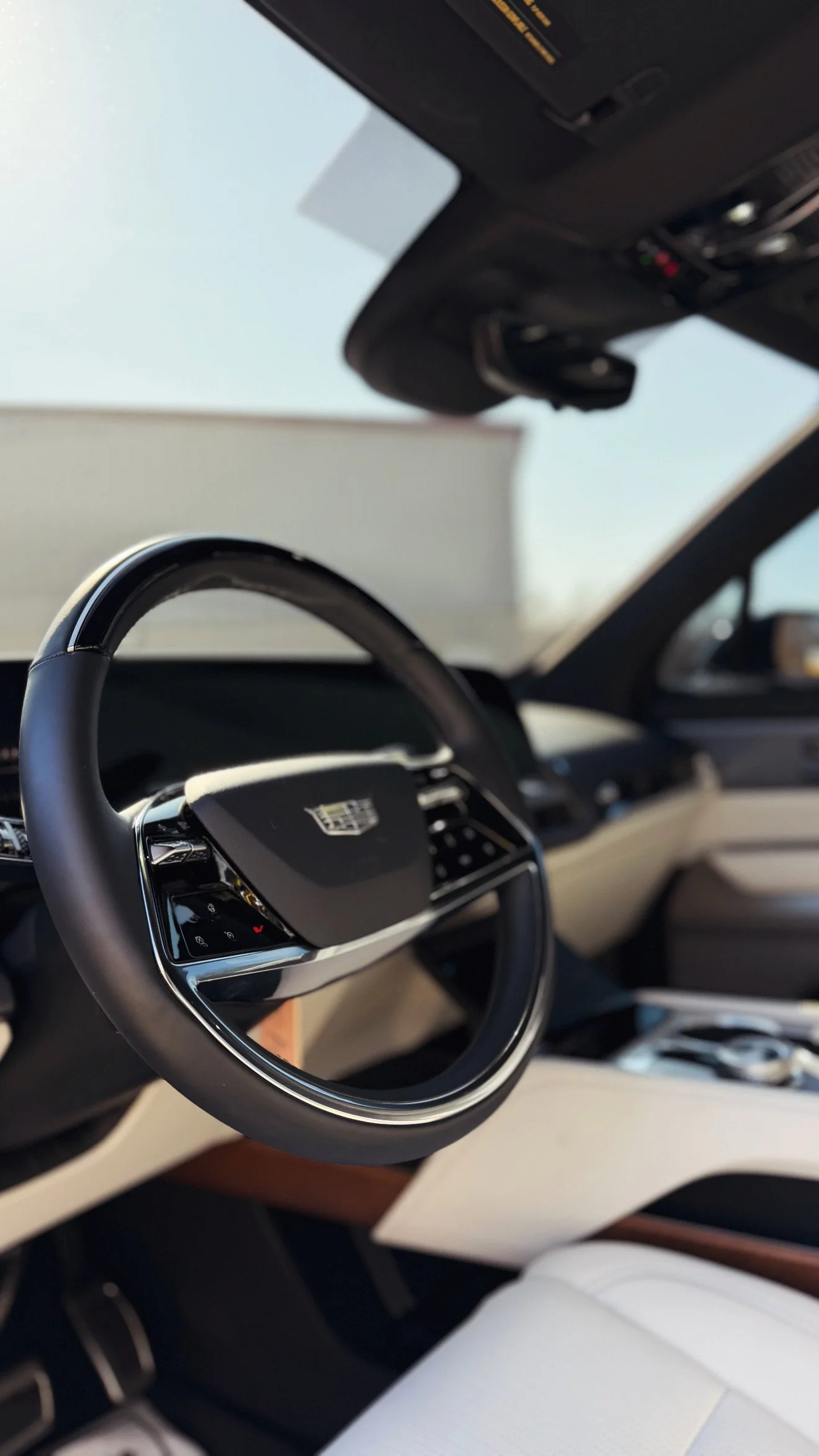 Interior of a luxury car, featuring a close-up of the steering wheel with a badge in the center and a dashboard with controls after a detail