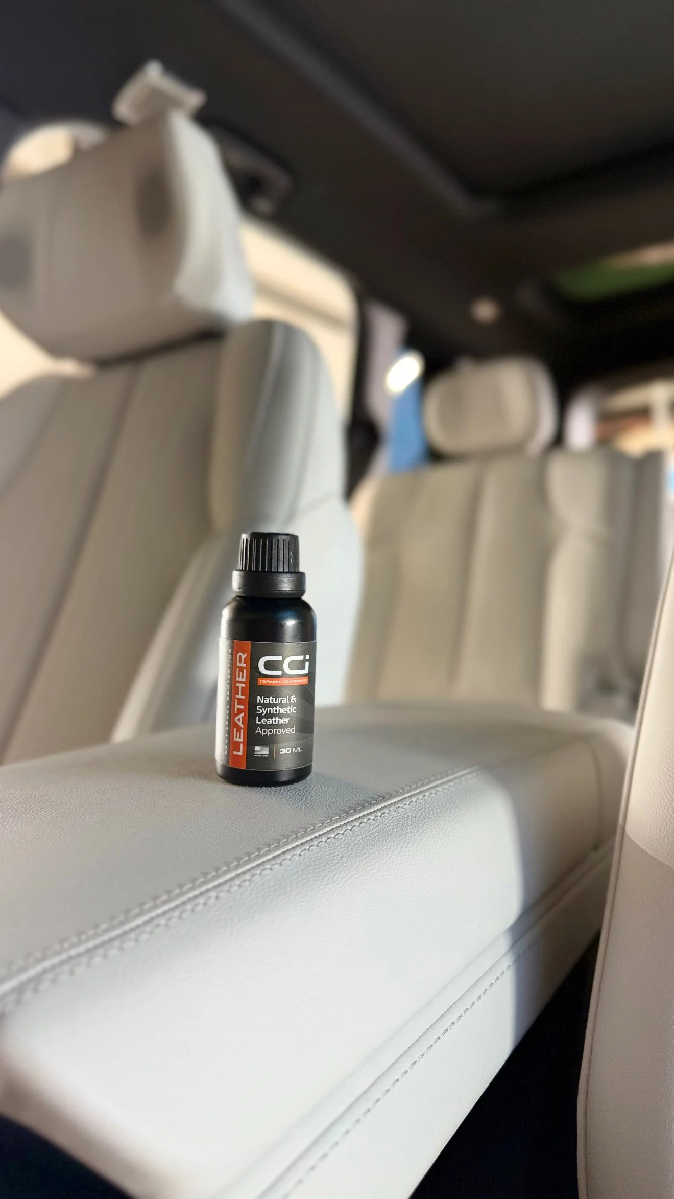 A small black bottle of leather ceramic placed on a white car seat.