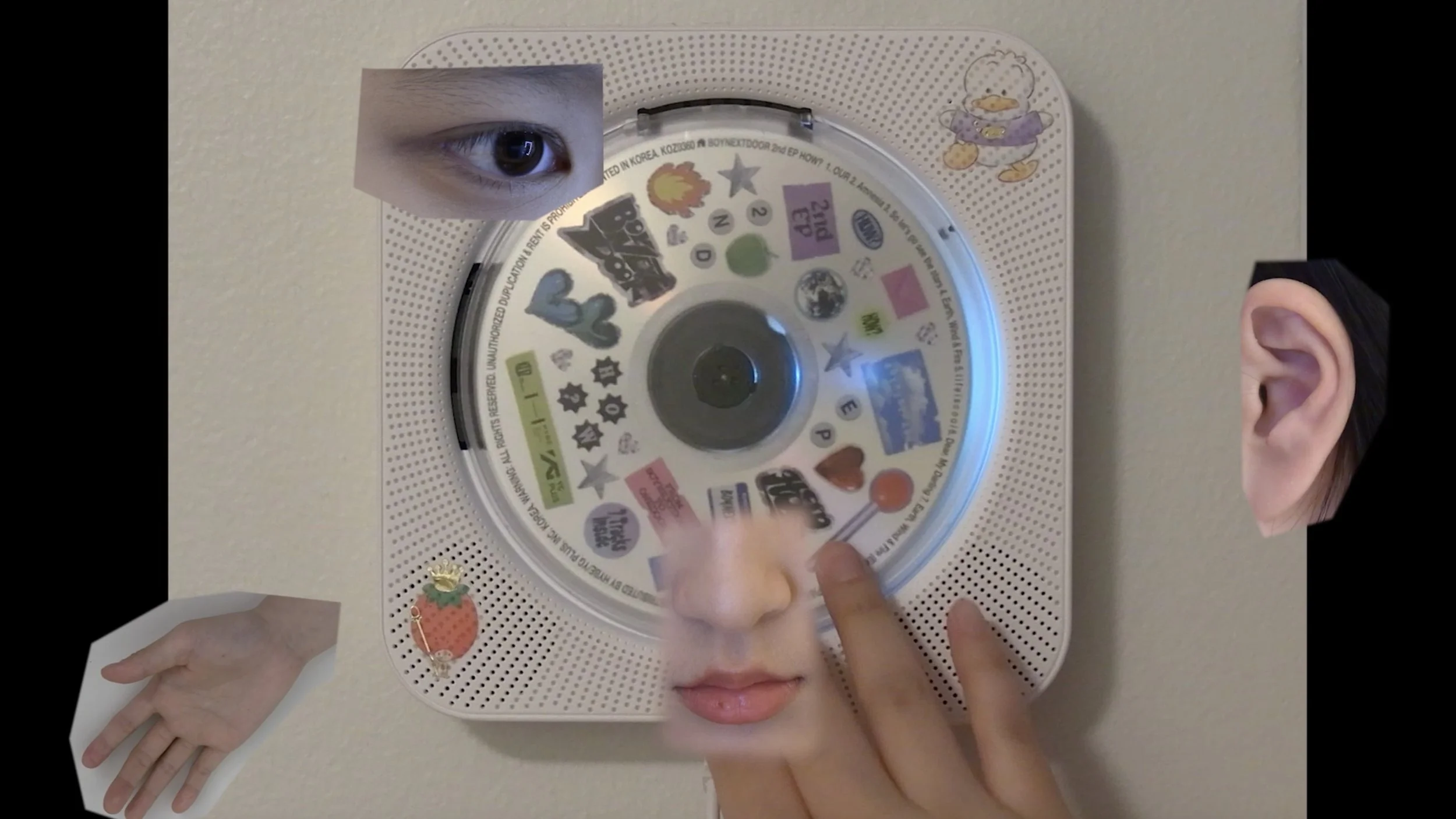 Mixed-media collage with parts of a person's face, an eye, a hand, and an ear overlapping a circular sticker collection on a speaker or clock, on a beige wall.