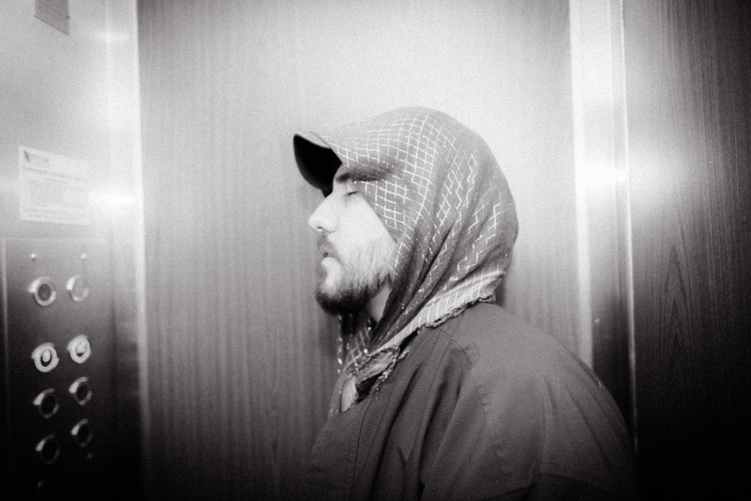 Hombre con barba y gorra con capucha en un ascensor