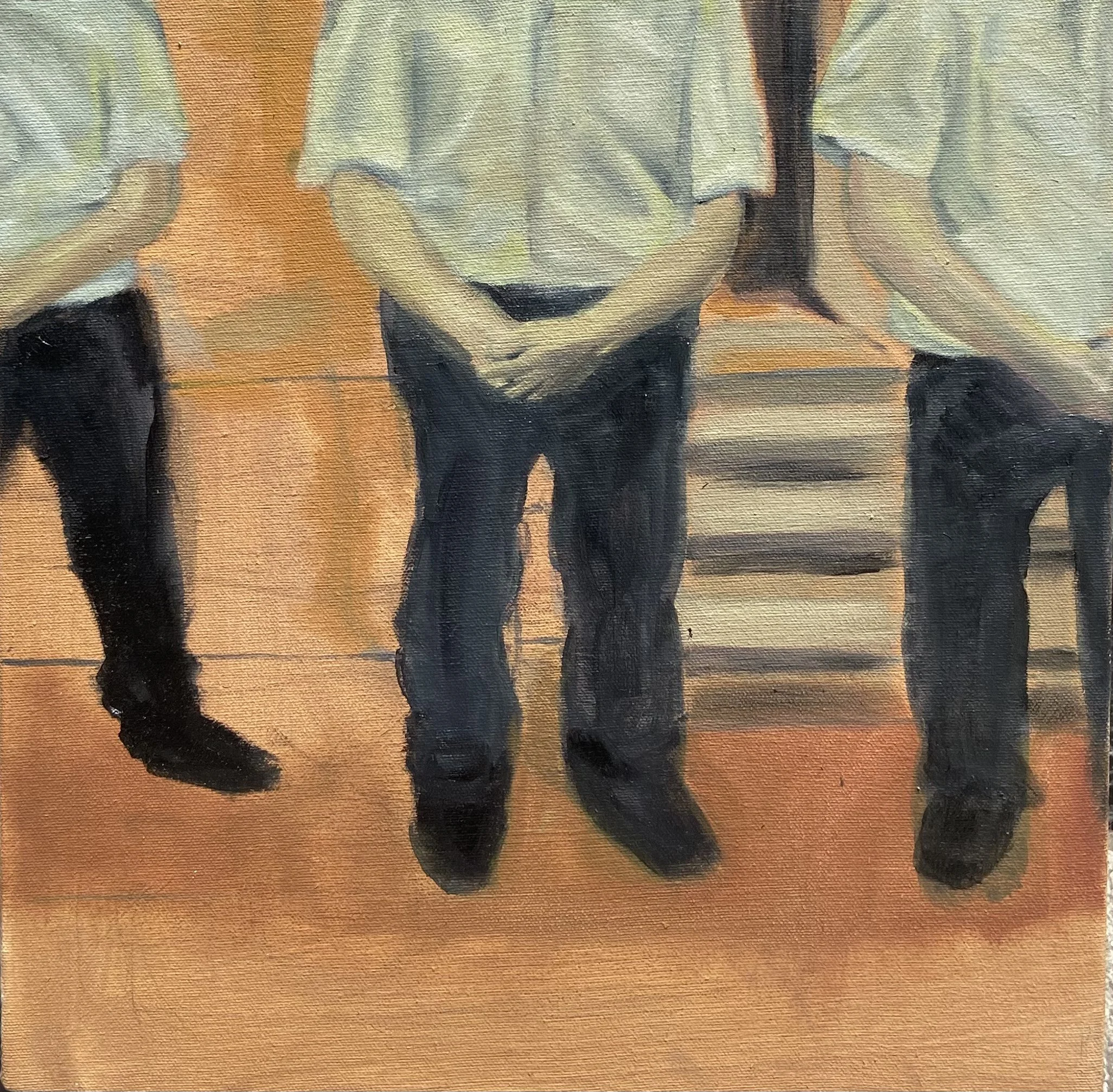 Cuatro personas con uniformes de trabajo, de las cuales sólo se ven partes del cuerpo, de pie sobre un piso de madera.