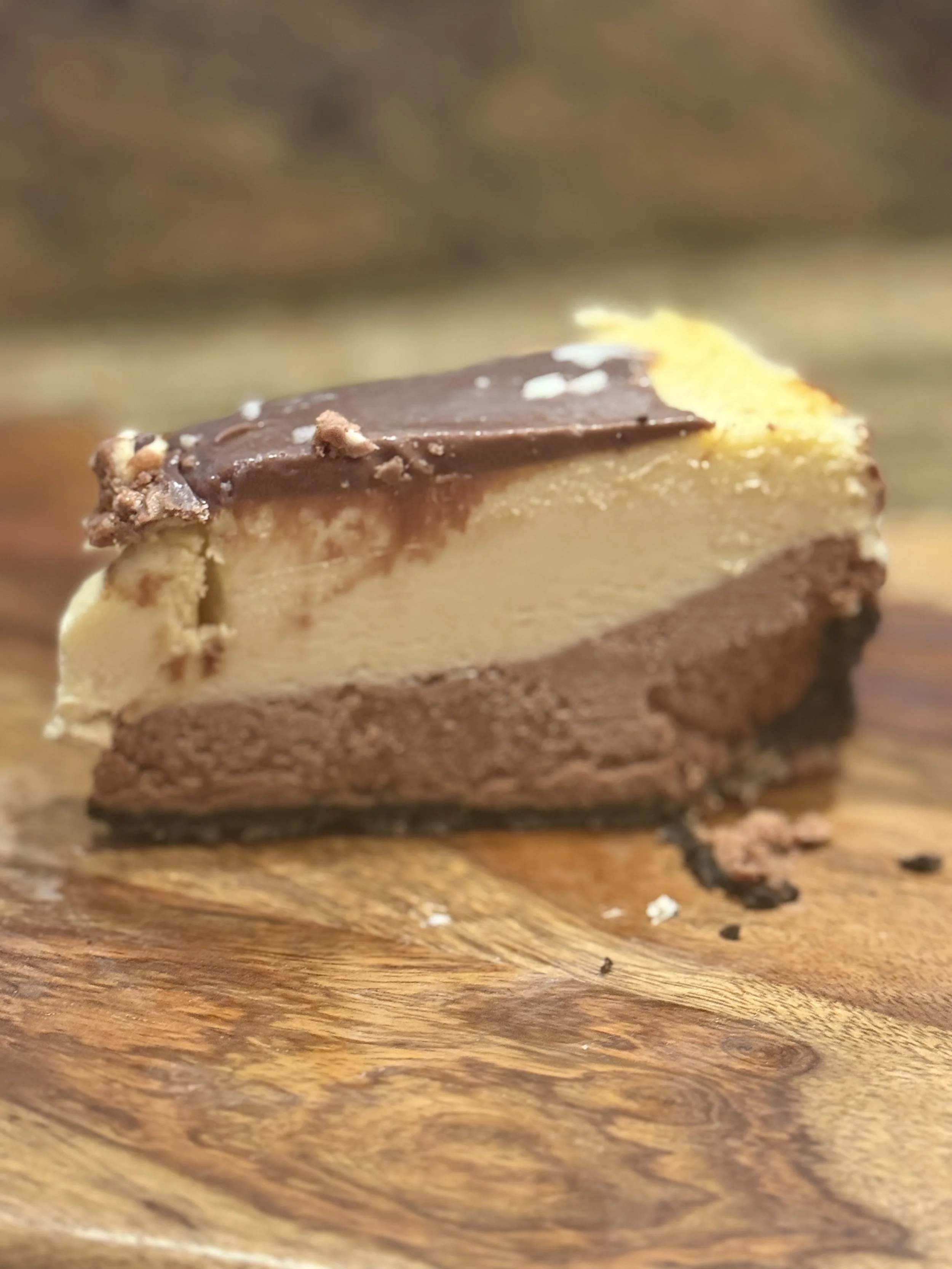 Layered triple chocolate cheesecake with a milk‑chocolate base, white‑chocolate top, and glossy ganache dripping down the sides