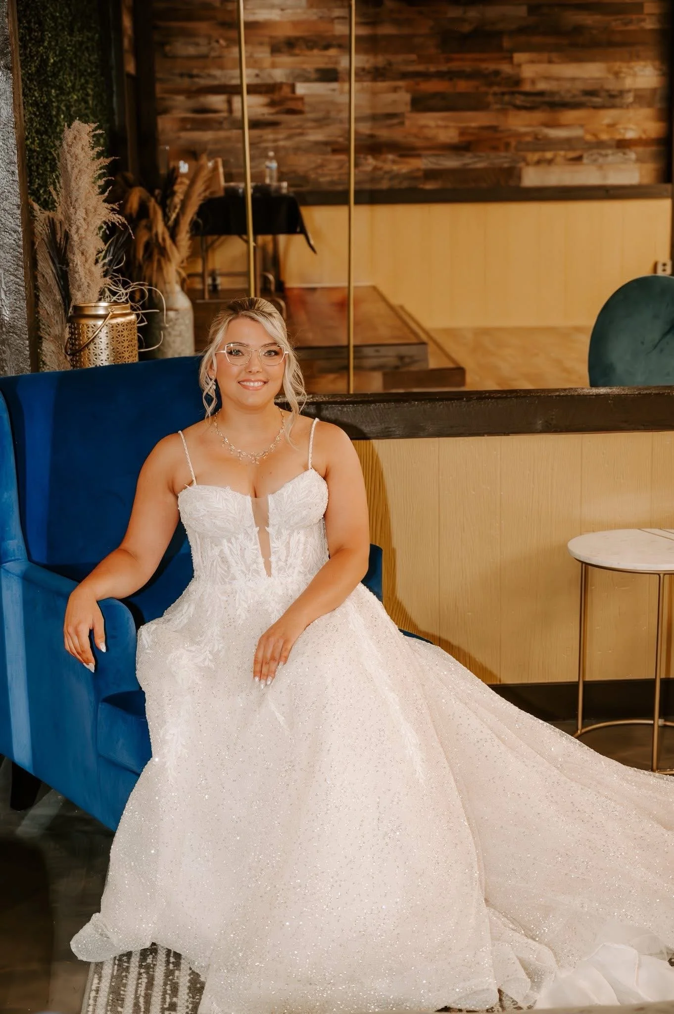 A smiling couple on their wedding day, outdoors in a grassy area with trees in the background, during golden hour lighting.