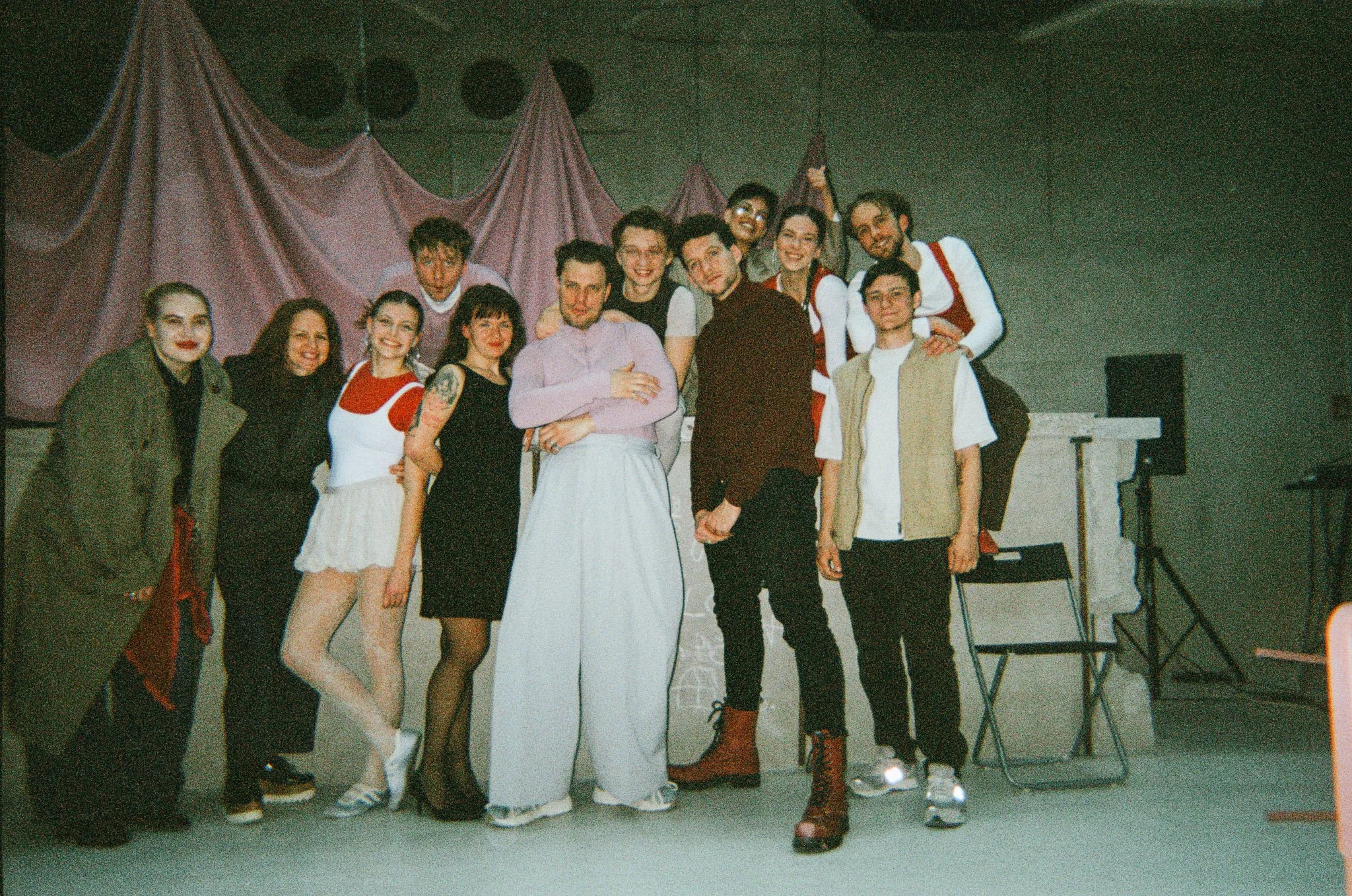 A group of people posing on stage in front of a pink curtain, likely after a performance or event.