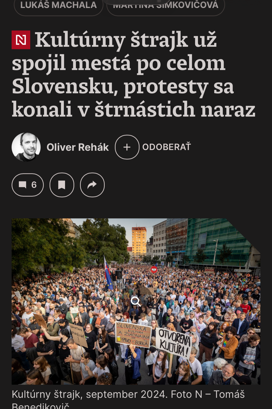 A large crowd of protesters gathered in an urban plaza, holding various signs including one that reads 'Otvoriť kultúru!' and another with Slovak language slogans, with buildings and trees in the background during daytime.