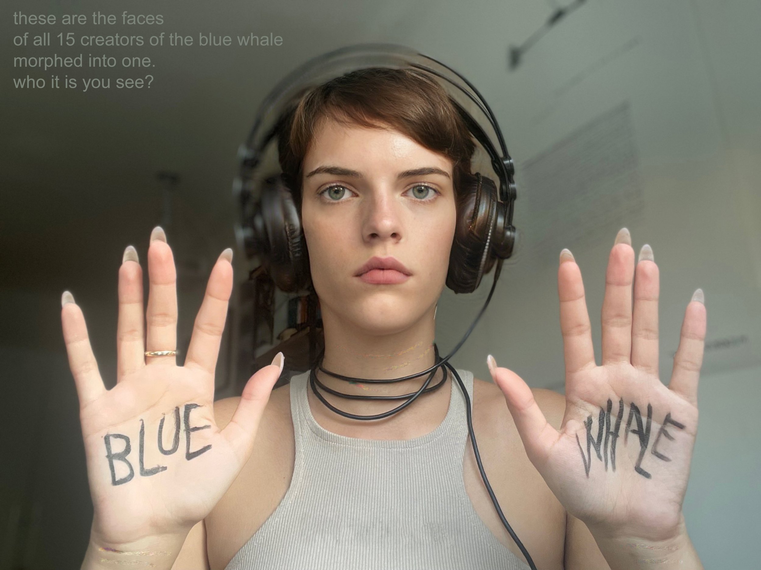 A young woman with short brown hair wearing large headphones and a light sleeveless top, holding up both hands with words 'BLUE' on her left palm and 'WHITE' on her right palm, in front of a mirror or glass surface.