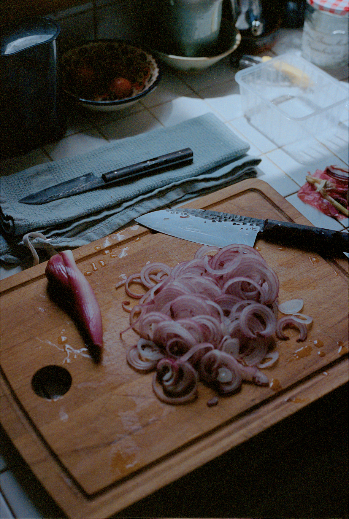 Chopping board with sliced red onion and a whole onion on a kitchen counter.
