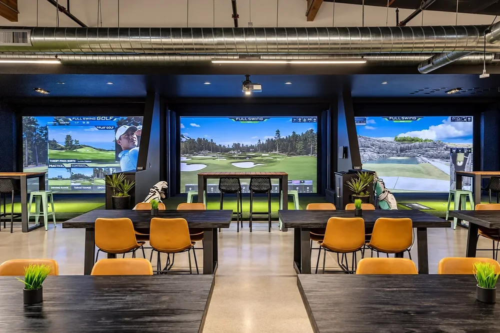Three simulator bays and long tables on the Bermuda Club main floor