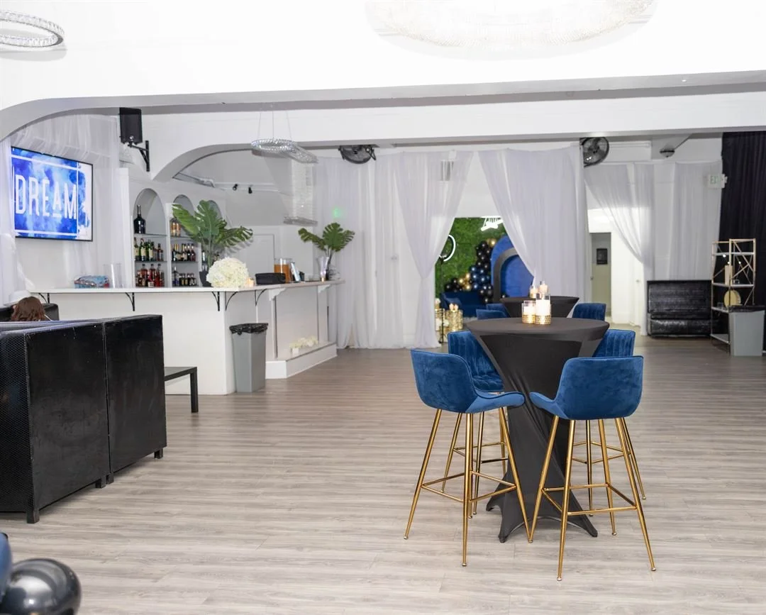 Dream SF bar area with blue upholstered stools and chandeliers overhead