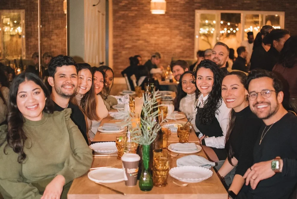 Friends making a toast at a long table inside Aracely Lounge