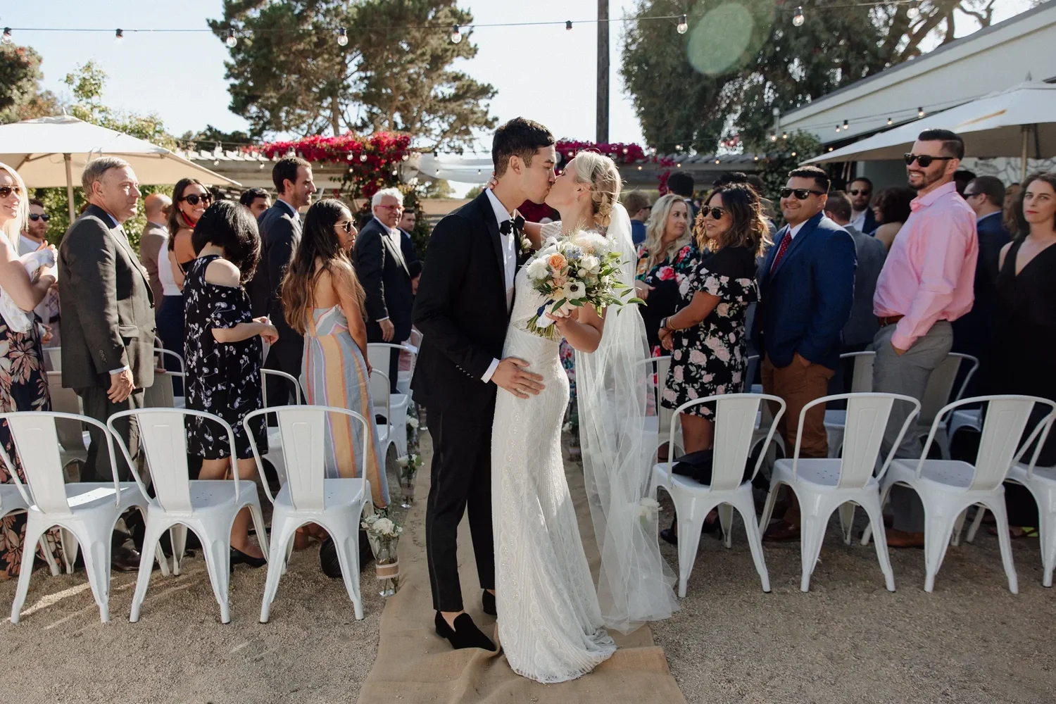 Newlyweds walking between seated guests in the Aracely Cafe garden