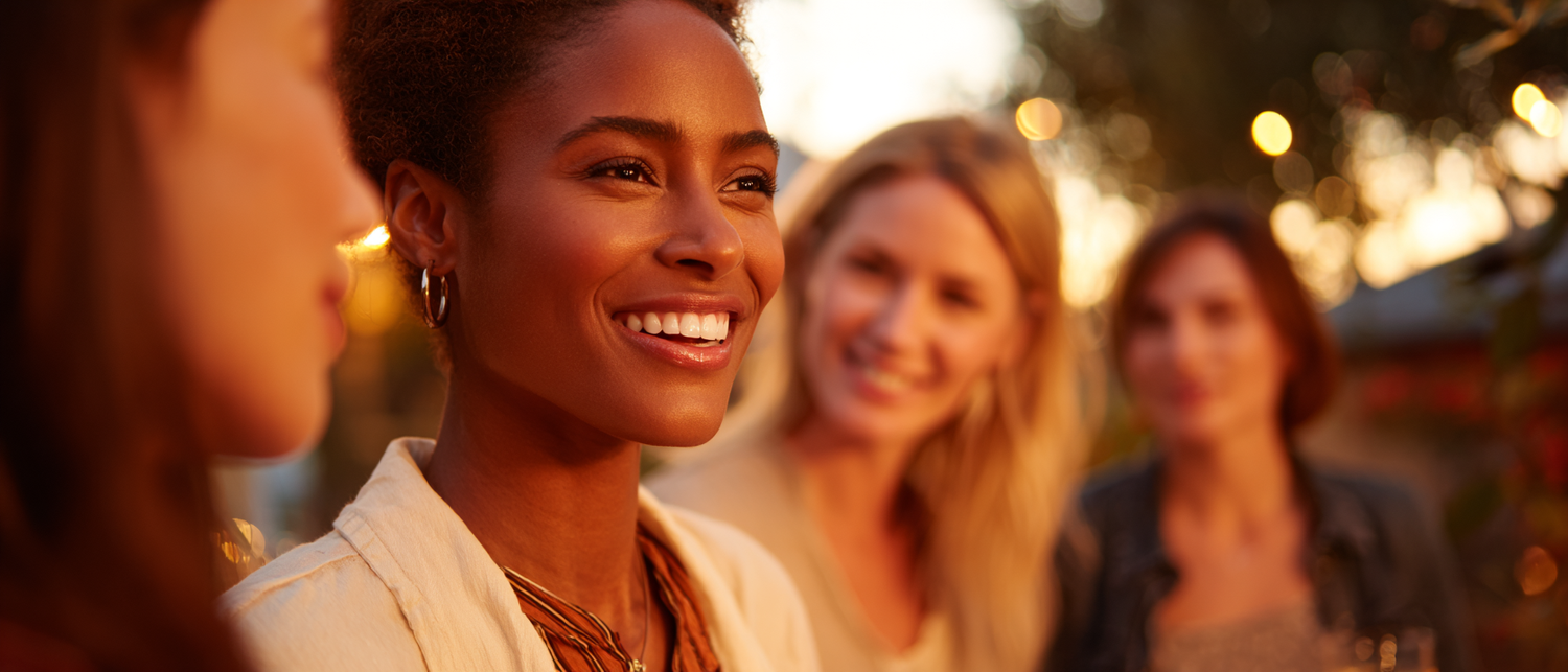 Guests at a private venue event at golden hour, woman smiling with friends outdoors