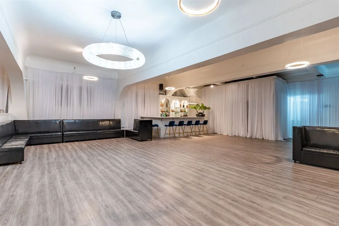 Dream SF bar area with blue upholstered stools and chandeliers overhead