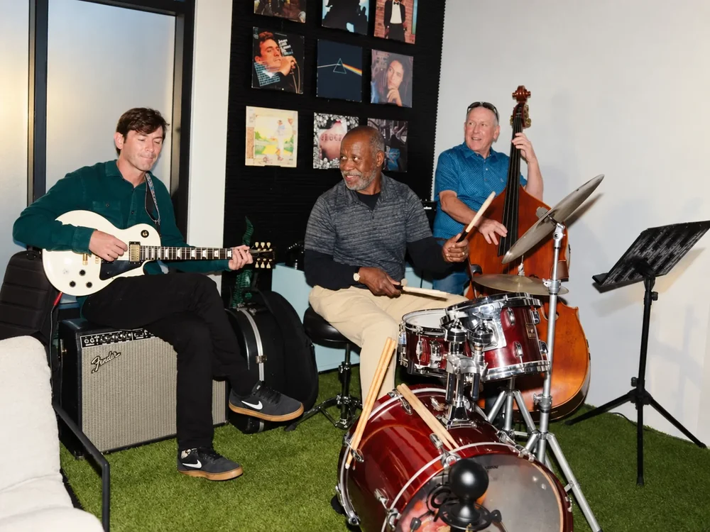 A guitarist, drummer and upright bass player performing at a private reception