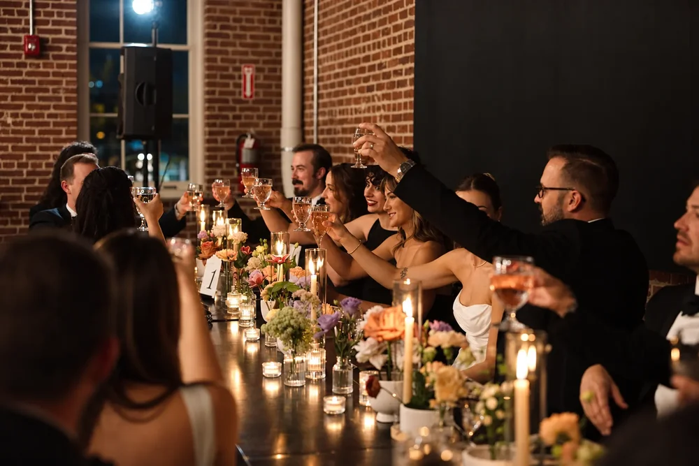 Guests raising glasses at a candlelit long table in a private dining room