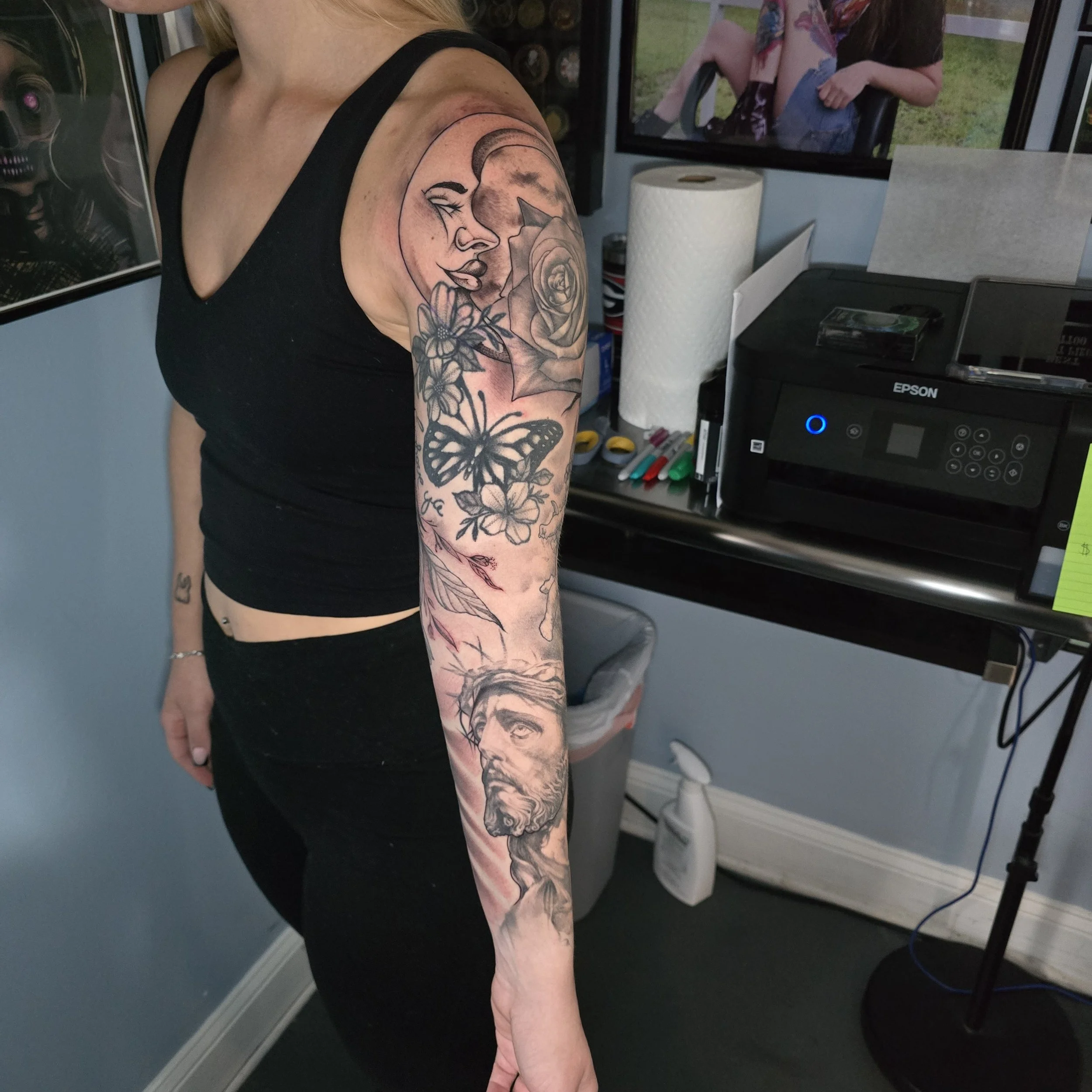 This client came to us with tattoos already filling a good portion of her arm.  We were able to add a portrait of Jesus, and a Catholic styed crucifix.  We then went in and added a Cherub and some clouds, and a nice moonface 
