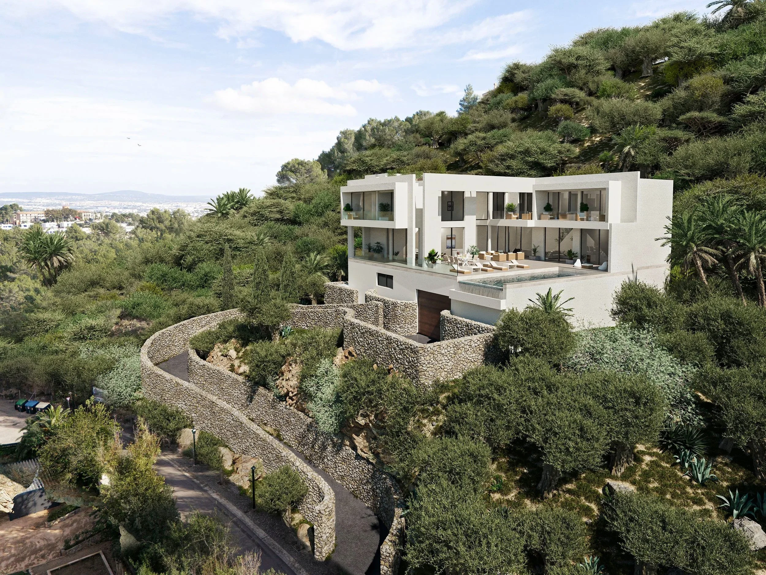 Modern white house with large glass windows and balconies, built into a hillside surrounded by green trees and plants, featuring a curved stone retaining wall and a pool area.