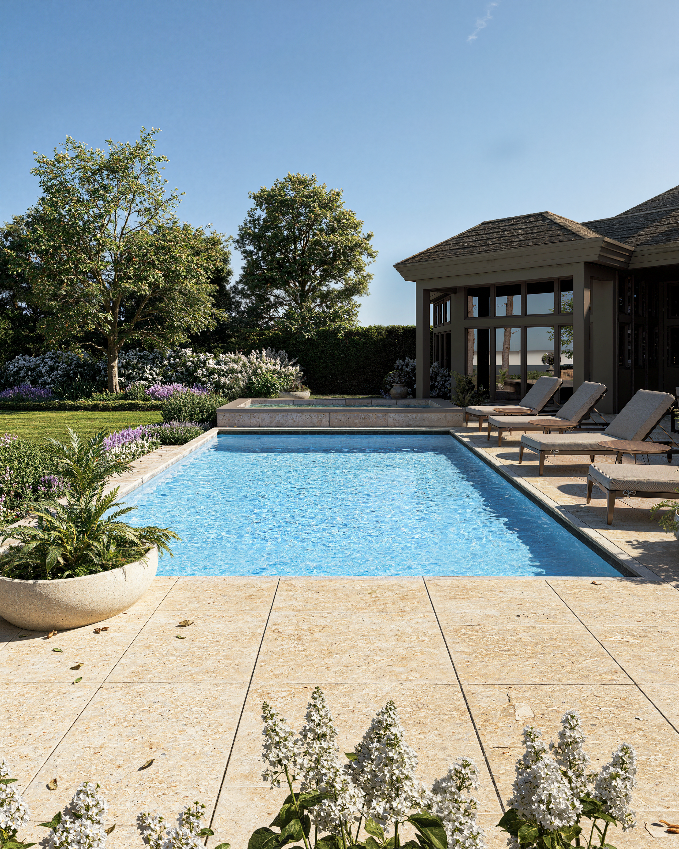 Landscape visualisation of a luxury pool garden with travertine paving, pool house and soft planting. Photorealistic CGI by DesignVis, Scotland.