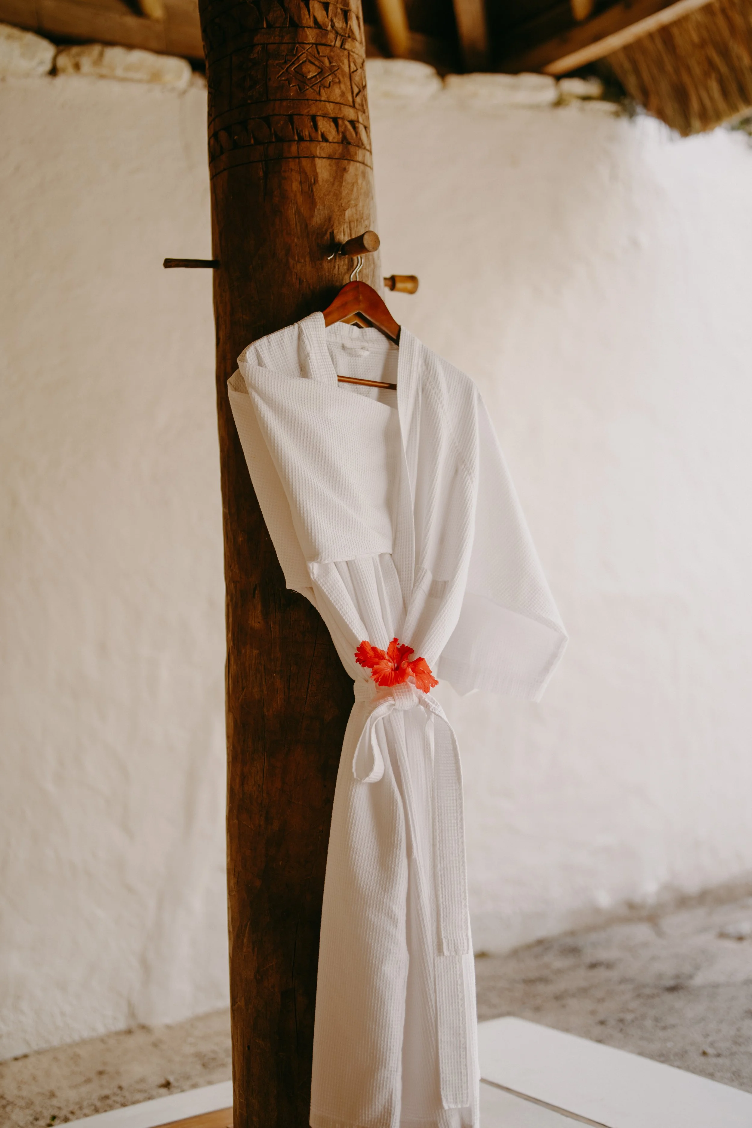 A white martial arts gi hanging on a wooden hook against a rustic wooden post.