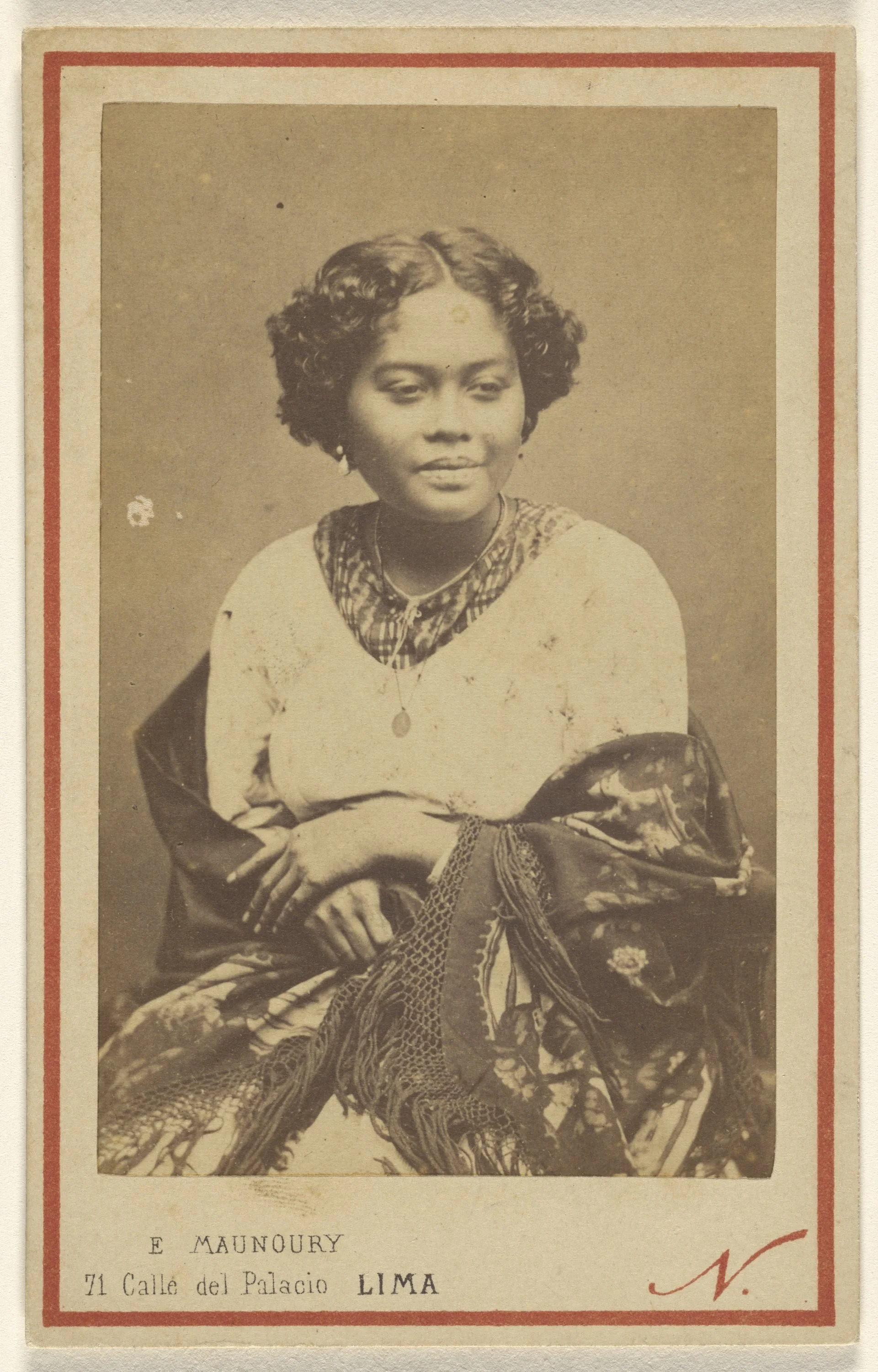Black and white portrait of a woman with short, curly hair, wearing a patterned scarf and jewelry, sitting with her hands folded.