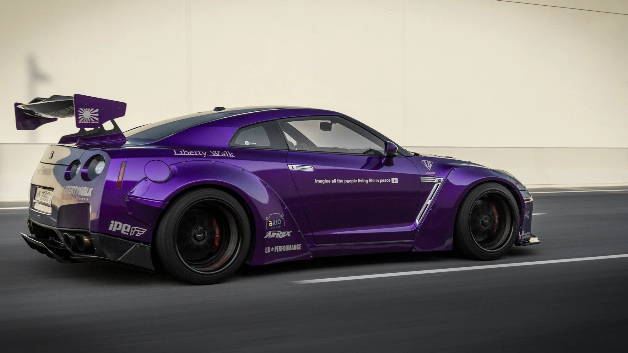 A purple race car with various sponsor logos, driving on a road in front of a plain white wall.