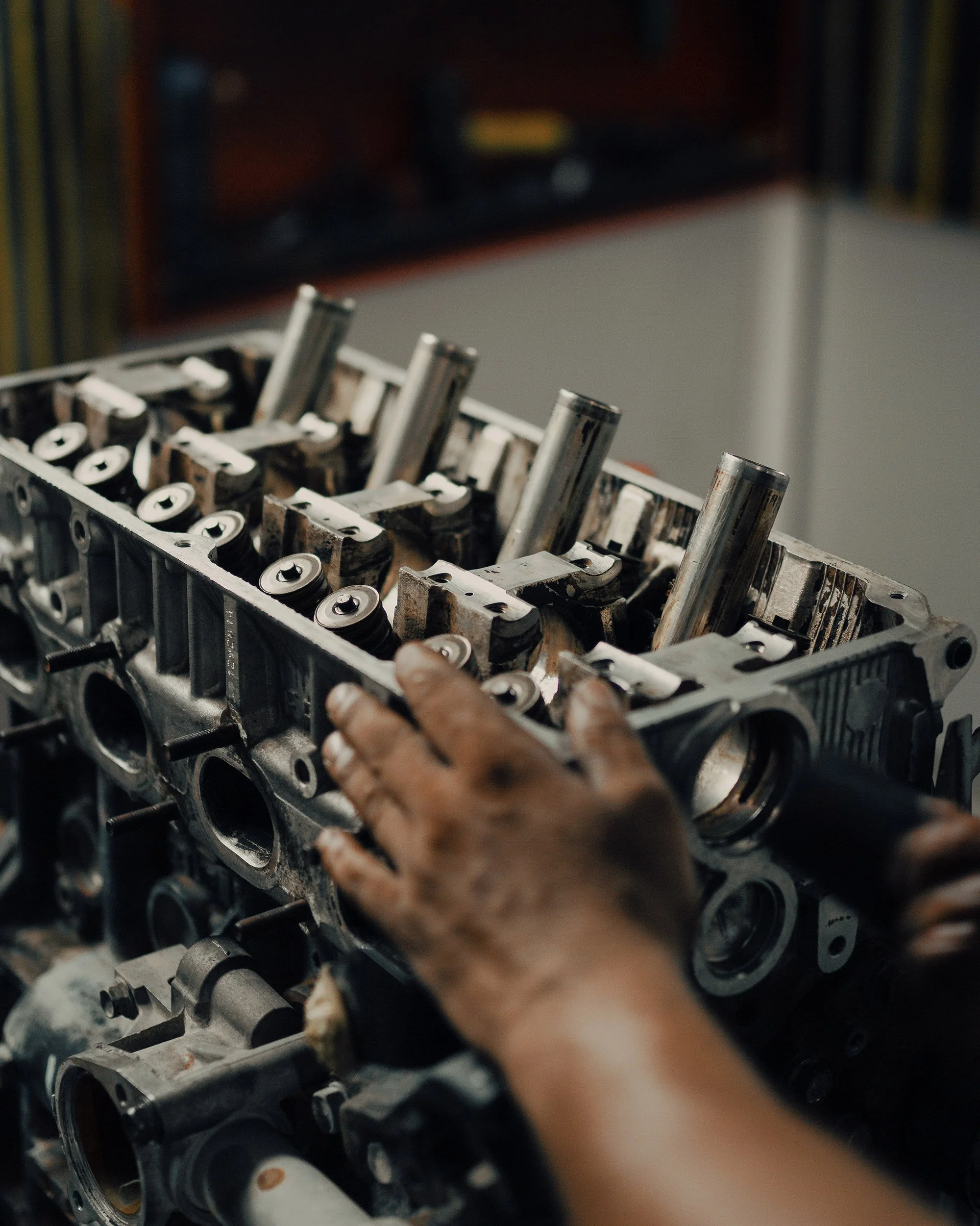 A person working on an engine cylinder head, placing components or inspecting the parts.