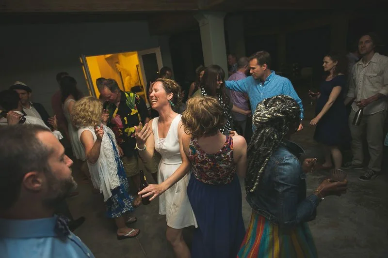 Group of people dancing and socializing at a party or celebration in a dimly lit room.