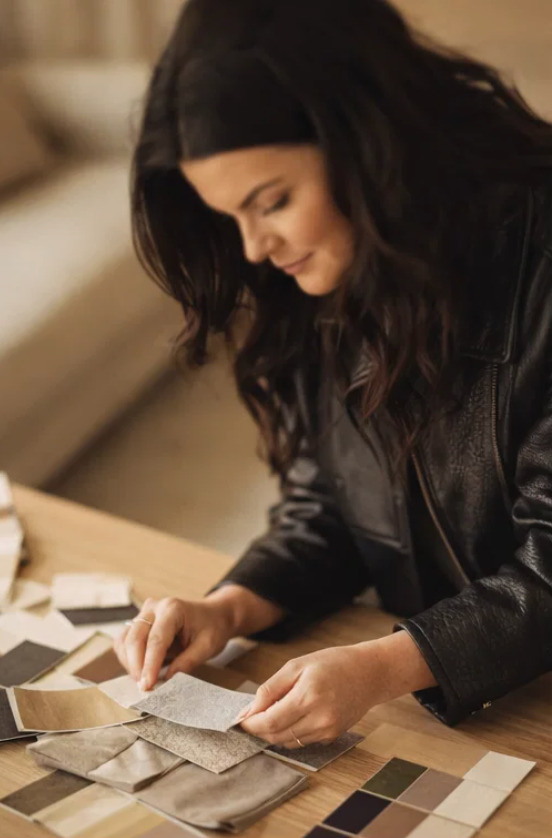Woman examining fabric swatches on a table.