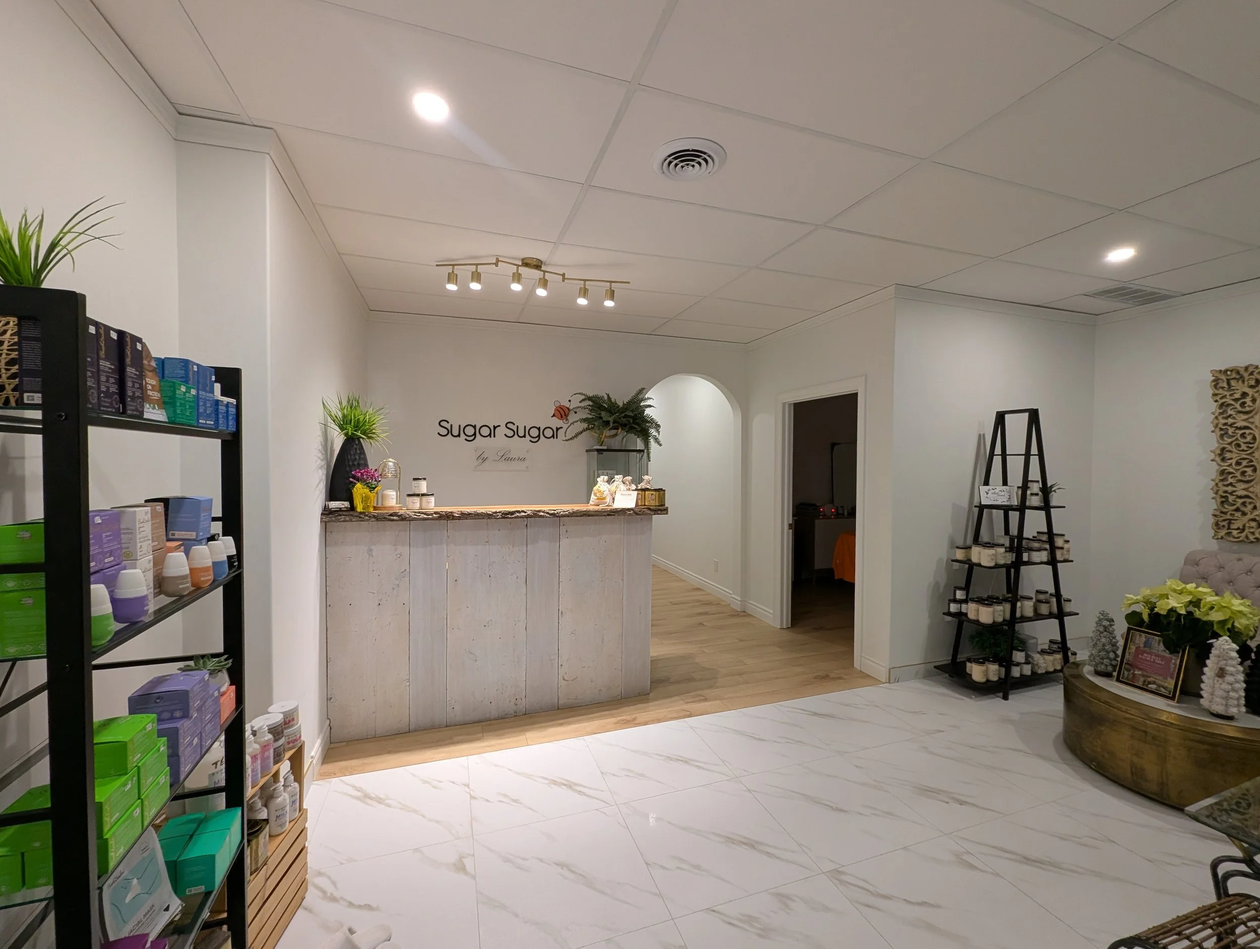 Interior of a boutique or spa with a reception desk, shelves with wellness products, and decorative plants.